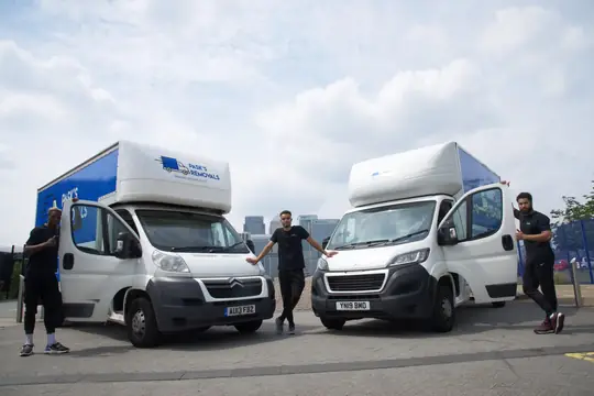 Three Pask's Removals London movers posing with two white Luton removal vans