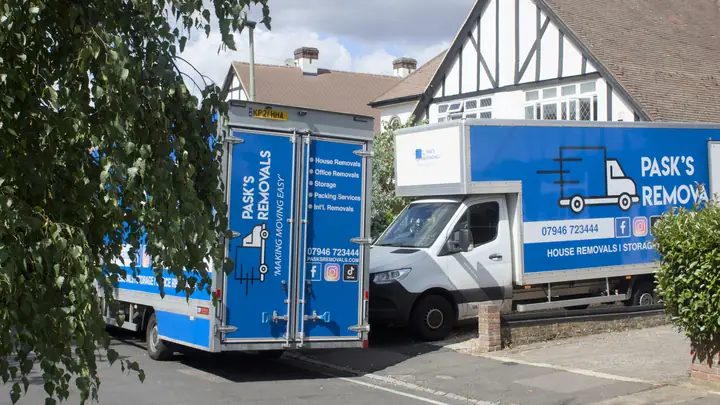 Two branded Pask's Removals London vans parked outside a mock-Tudor house