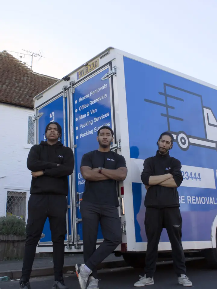 Three Pask’s Removals London movers with arms folded in front of a branded Luton van by a white cottage