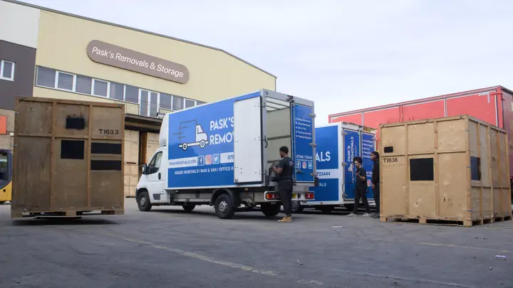 Pask's Removals London crew loading vans outside the Pask's Removals & Storage warehouse beside wooden storage crates