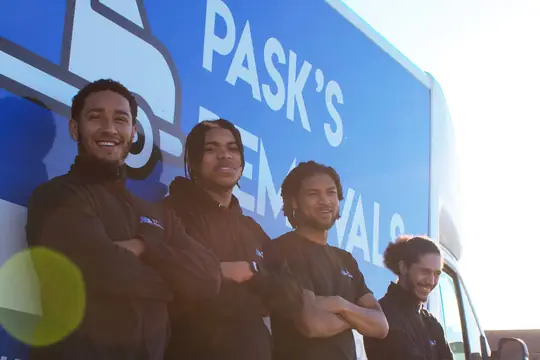Four Pask's Removals London crew members leaning against the side of their branded van
