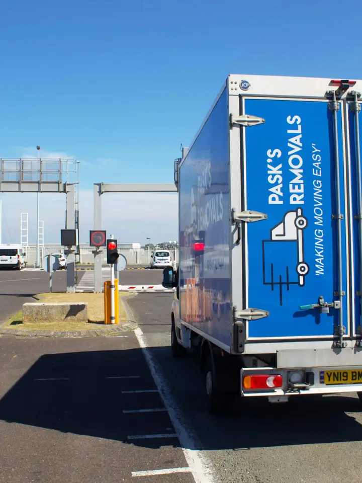 Rear of a Pask’s Removals London van in a port check-in lane with French and English signs