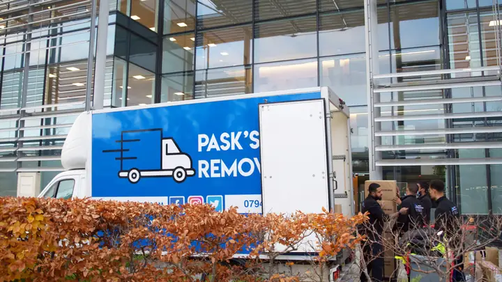 Pask's Removals London crew unloading boxes from the branded van outside a glass office building