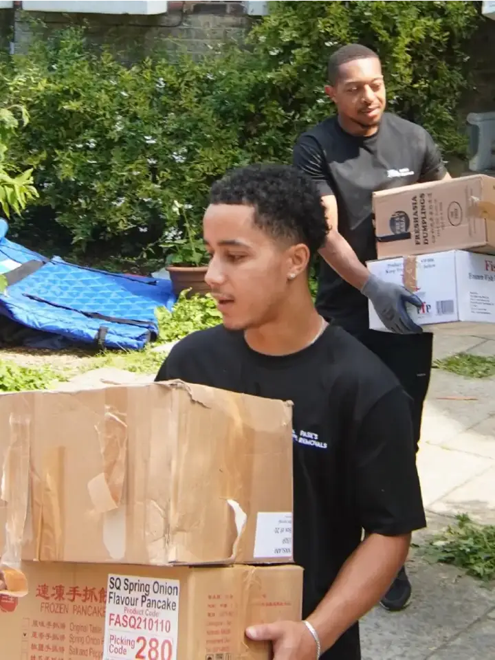 Two Pask's Removals London movers carrying cardboard boxes out of a house